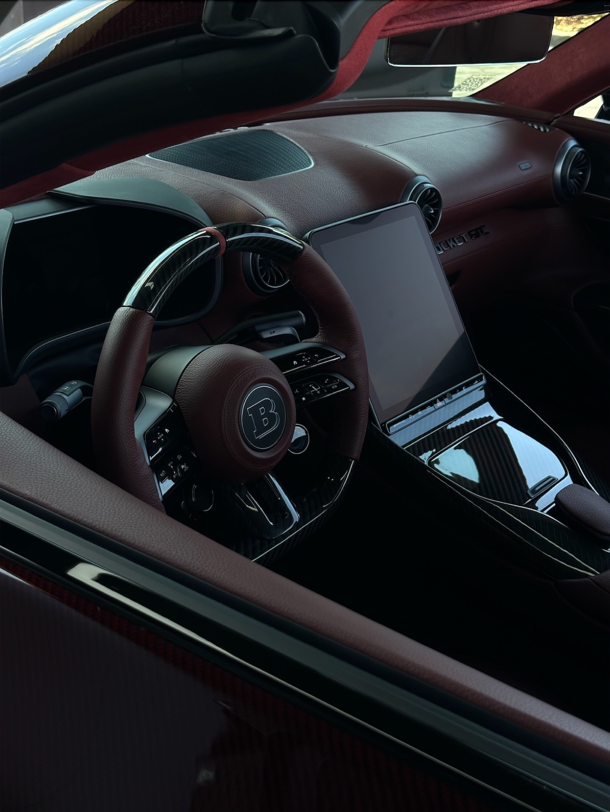 Detailed cockpit of a Brabus with maroon leather, carbon trim, and steering wheel