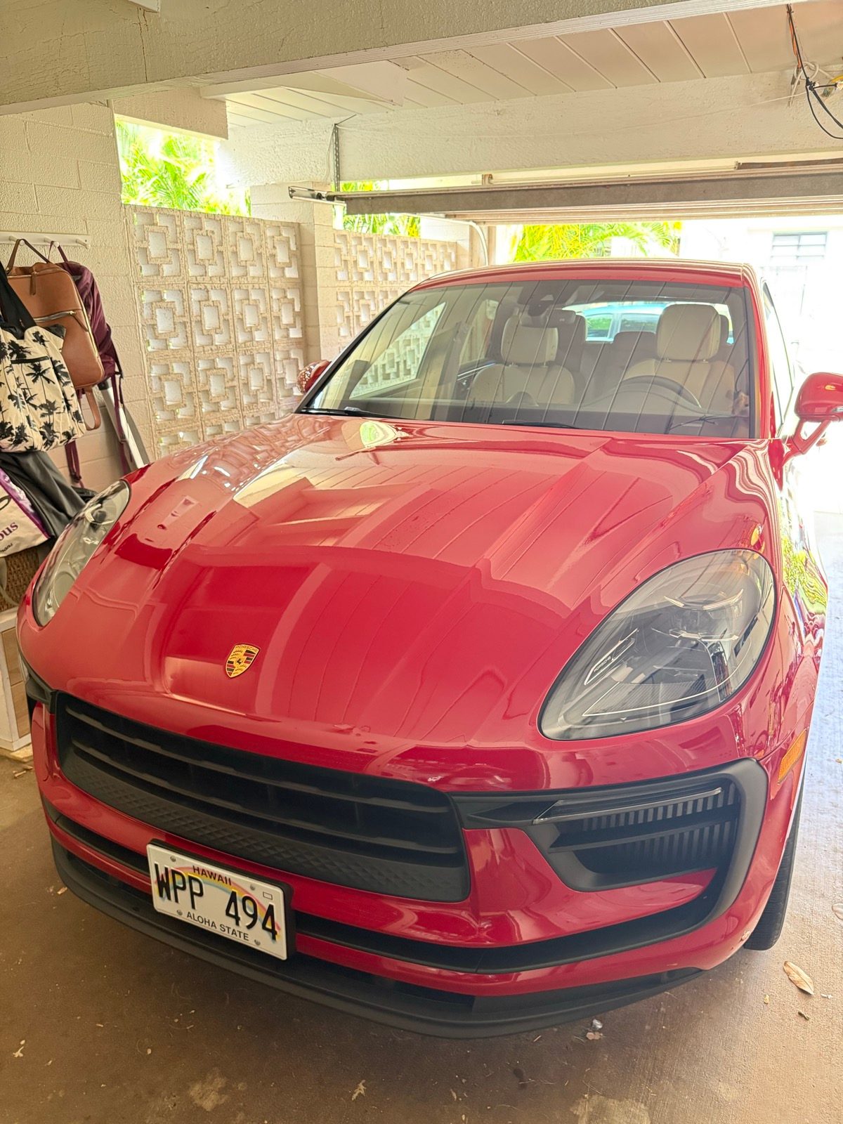 Detailed red Porsche Macan in a carport with Hawaii plates